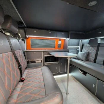 Wide interior view of Spartan’s camper kitchen with bold colour contrast and sleek design