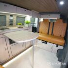 Rock and roll bed upholstered in fudge trim in VW T6.1 LWB campervan layout