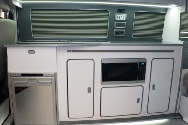 Interior view of Spartan campervan kitchen featuring white gloss units and steel worktop VW T6.1