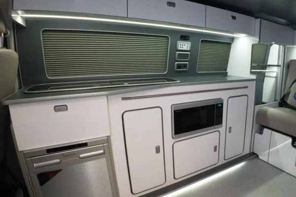Interior view of Spartan campervan kitchen featuring white gloss units and steel worktop VW T6.1