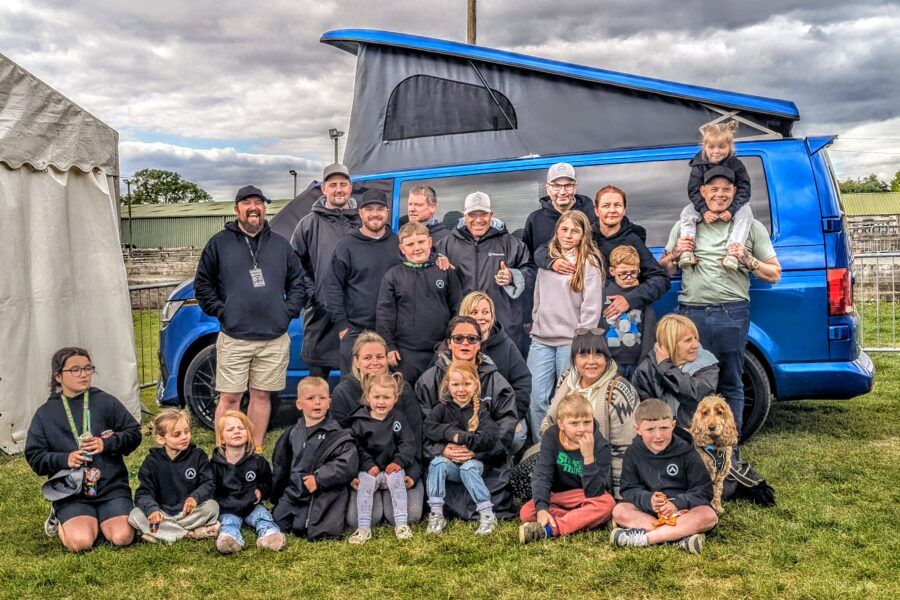 Spartan Campers family gathered around the VW campervan signed by Levi Roots during Campout 2025 at the Warners Show