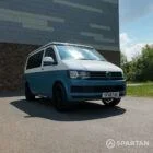 Front passenger side view of Spartan Campers VW T6 campervan with poptop roof closed in candy white and Neptune blue