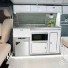 Spartan campervan kitchen featuring white units and silver birch worktops, expertly crafted for style and function