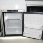 Integrated fridge unit in Spartan campervan, seamlessly fitted into the white and silver birch kitchen for convenient cold storage on the go