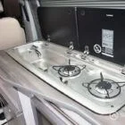 Sink and hob integrated into white and silver birch kitchen on winter floor in VW T6.1 SWB campervan