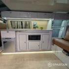 Interior kitchen view of VW T6.1 LWB campervan with latte cabinets, Winchester Oak detail, and Champagne Oak flooring