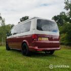 Rear passenger quarter view of VW T6.1 Business Pack LWB campervan, pop-top roof down, Fortana Red and Candy White