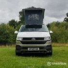 Head-on view of VW T6.1 LWB campervan with pop-top roof up, Military Green and Candy White