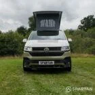 Head-on view of VW T6.1 Highline SWB campervan with pop-top roof up, Military Green and Candy White
