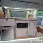 Close-up of VW T6.1 Highline SWB campervan kitchen showing integrated hob and oak splashback