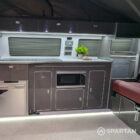 Interior kitchen view of VW T6.1 Business Pack LWB campervan with slate grey cabinets, white detail, and winter flooring
