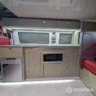 VW T6 LWB Deep Black campervan kitchen with olive green cabinetry, latte accents, and winter flooring