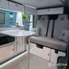 Luxury campervan conversion interior by Spartan with dining seats, compact kitchen, and fitted appliances.