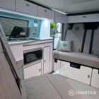 Compact campervan kitchen in Spartan SWB conversion featuring glossy cabinets, worktop, and built-in appliances.