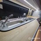 Modern campervan kitchen in latte and bardolino oak finish with built-in fridge, hob, and oak flooring.