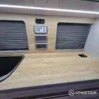 Close-up of campervan kitchen area featuring latte and bardolino oak units, worktop, and integrated appliances.