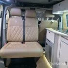 Luxury campervan interior showing latte cabinetry, natural bardolino oak accents, and rich liquor leather seating.