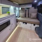 Spartan SWB campervan interior with champagne oak flooring, latte kitchen units, and liquor upholstery seating.