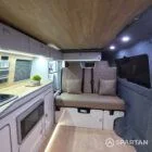 Compact campervan kitchen and seating finished in latte and bardolino oak with champagne oak flooring.