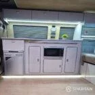 Campervan lounge view with liquor upholstery seating beside latte and oak kitchen furniture.