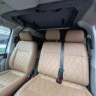 Interior of Spartan Conversion VW T6 featuring winter flooring, latte main units with driftwood detailing, and liquor upholstery seating.