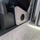 Interior of Spartan Conversion VW T6 featuring winter flooring, latte main units with driftwood detailing, and liquor upholstery seating.