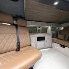 Interior of Spartan Conversion VW T6 featuring winter flooring, latte main units with driftwood detailing, and liquor upholstery seating.