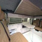 Interior of Spartan Conversion VW T6 featuring winter flooring, latte main units with driftwood detailing, and liquor upholstery seating.