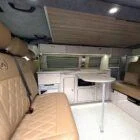 Interior of Spartan Conversion VW T6 featuring winter flooring, latte main units with driftwood detailing, and liquor upholstery seating.
