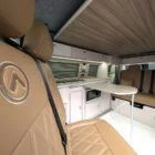 Interior of Spartan Conversion VW T6 featuring winter flooring, latte main units with driftwood detailing, and liquor upholstery seating.