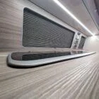 Interior of Spartan Conversion VW T6 featuring winter flooring, latte main units with driftwood detailing, and liquor upholstery seating.