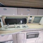 Interior of Spartan Conversion VW T6 featuring winter flooring, latte main units with driftwood detailing, and liquor upholstery seating.
