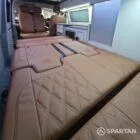 Interior of a Spartan Campers conversion featuring a champagne oak floor, latte and Winchester oak kitchen units, and toffee-coloured upholstery, creating a warm, modern, and cosy living space.