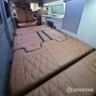 Interior of a Spartan Campers conversion featuring a champagne oak floor, latte and Winchester oak kitchen units, and toffee-coloured upholstery, creating a warm, modern, and cosy living space.