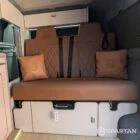 Interior of a Spartan Campers conversion featuring a champagne oak floor, latte and Winchester oak kitchen units, and toffee-coloured upholstery, creating a warm, modern, and cosy living space.