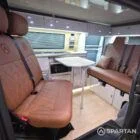 Interior of a Spartan Campers conversion featuring a champagne oak floor, latte and Winchester oak kitchen units, and toffee-coloured upholstery, creating a warm, modern, and cosy living space.