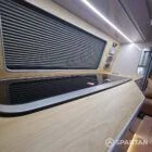 Interior of a Spartan Campers conversion featuring a champagne oak floor, latte and Winchester oak kitchen units, and toffee-coloured upholstery, creating a warm, modern, and cosy living space.