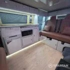 Interior of a Spartan Campers conversion featuring a champagne oak floor, latte and Winchester oak kitchen units, and toffee-coloured upholstery, creating a warm, modern, and cosy living space.