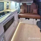 Interior of a Spartan Campers conversion featuring a champagne oak floor, latte and Winchester oak kitchen units, and toffee-coloured upholstery, creating a warm, modern, and cosy living space.