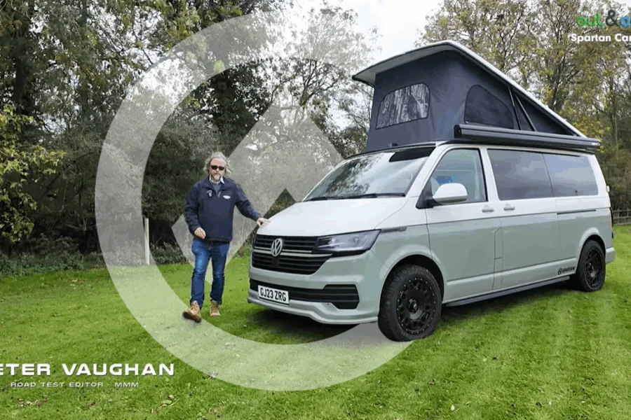 Peter Vaughan standing beside the new 2025 Spartan T6.1 campervan, showcasing its sleek VW Transporter body with the pop-top roof raised and the side door open to reveal the modern interior.