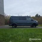 Volkswagen T6.1 long-wheelbase in Pure Grey, fitted with a Spartan camper conversion featuring the slide-and-swivel bench, clean interior lines and subtle exterior styling, parked outdoors.