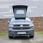 Volkswagen T6.1 long-wheelbase in Pure Grey, fitted with a Spartan camper conversion featuring the slide-and-swivel bench, clean interior lines and subtle exterior styling, parked outdoors.