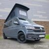 Volkswagen T6.1 long-wheelbase in Pure Grey, fitted with a Spartan camper conversion featuring the slide-and-swivel bench, clean interior lines and subtle exterior styling, parked outdoors.