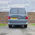 Volkswagen T6.1 long-wheelbase in Pure Grey, fitted with a Spartan camper conversion featuring the slide-and-swivel bench, clean interior lines and subtle exterior styling, parked outdoors.