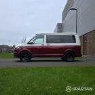 Volkswagen T6.1 short-wheelbase in Candy White and Fortana Red, fitted with a Spartan camper conversion, showing the clean interior layout, modular storage and signature slide-and-swivel bench.