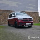 Volkswagen T6.1 short-wheelbase in Candy White and Fortana Red, fitted with a Spartan camper conversion, showing the clean interior layout, modular storage and signature slide-and-swivel bench.