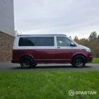 Volkswagen T6.1 short-wheelbase in Candy White and Fortana Red, fitted with a Spartan camper conversion, showing the clean interior layout, modular storage and signature slide-and-swivel bench.