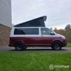 Volkswagen T6.1 short-wheelbase in Candy White and Fortana Red, fitted with a Spartan camper conversion, showing the clean interior layout, modular storage and signature slide-and-swivel bench.