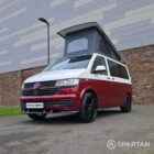 Volkswagen T6.1 short-wheelbase in Candy White and Fortana Red, fitted with a Spartan camper conversion, showing the clean interior layout, modular storage and signature slide-and-swivel bench.
