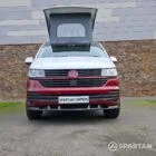 Volkswagen T6.1 short-wheelbase in Candy White and Fortana Red, fitted with a Spartan camper conversion, showing the clean interior layout, modular storage and signature slide-and-swivel bench.